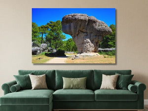 Tableau photo de paysage naturel représentant un rocher sculpté par l'érosion, accroché au-dessus d'un canapé vert dans un salon moderne.