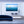 Modern living room with blue velvet sofa and large wall art of people boating on calm blue water