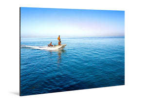 Small motorboat with people cruising on calm blue ocean under clear sky