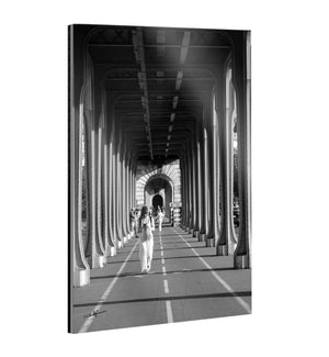 Tableau en plexiglas noir et blanc montrant une femme sous les arches métalliques du pont de Bir-Hakeim à Paris