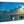 Glossy aluminum photo print of a waterfront scene with boats, clouds, and a child wading.