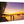 Glossy aluminum photo print of sunset beach scene with palm trees, people, and boats.