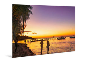 Glossy aluminum photo print of sunset beach scene with palm trees, people, and boats.