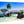 Aluminum photo print of tropical beach with wooden bridge, palm trees, blue sky, and clear water