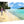 Aluminum photo print of tropical beach scene with palm trees, turquoise water, and people walking on sand