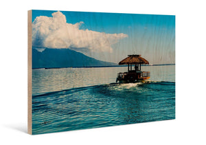 Direct print on wood of a tropical boat on calm blue water with mountains and clouds