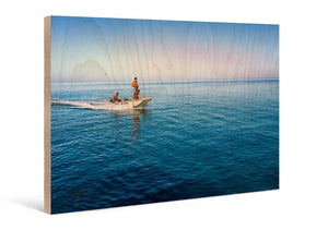 Direct print of boat on blue ocean with two people, displayed on natural wood panel