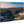 Artistic landscape photo print on wood showing forested hills, small bay, and blue sky.