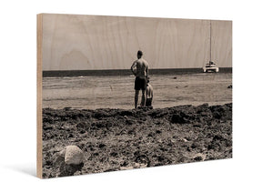 Sepia-toned photo print on wood showing two people by the sea with a sailboat in the distance.