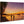 Sunset beach scene with silhouettes, palm tree, pier, and boats printed on wood panel