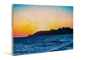 Direct print on wood of a colorful seascape at sunset with rocky coastline.