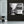 Modern living room with gray armchair, side table, and black and white tram cityscape wall art