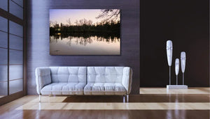 Modern living room with white sofa, wall art of lake sunset, and abstract face sculptures