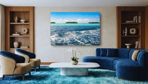 Modern living room with blue velvet sofa, ocean landscape wall art, and wood shelving