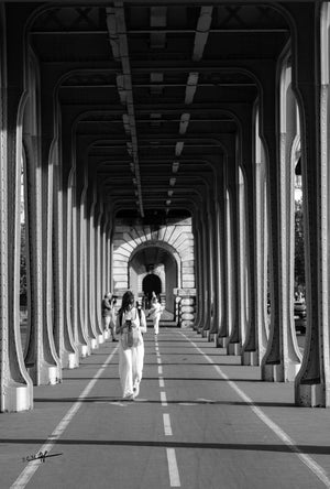 Image noir et blanc montrant une femme sous les arches métalliques du pont de Bir-Hakeim à Paris