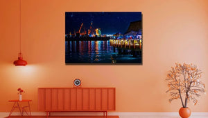 Modern living room with orange decor, featuring a wall art print of a vibrant night cityscape with water reflections.