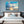Modern bedroom with a large cloudscape sky photo print above the bed, blue and white decor