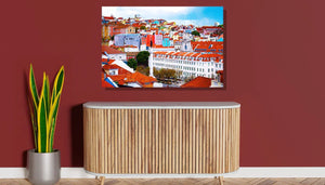 Colorful cityscape wall art above wood cabinet on red wall, with green indoor plant