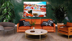 Modern living room with orange sofa, green plants, and colorful cityscape wall art
