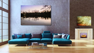 Modern living room with teal sofa, glass table, nature wall art, and fireplace