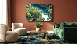Modern living room with a green sofa, armchairs, and wall art of a river and forest landscape