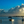 Peaceful seascape at sunset with dramatic clouds, small boats, and a child standing in shallow water