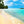 Tropical beach with turquoise water, palm trees, and people walking on sandy shore