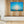 Framed sailboat photography print with blue sea and sky, displayed in a modern living room