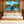 Modern lobby with wooden walls, white sofa, large potted plants, and yacht artwork on display.
