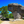 Mushroom-shaped rock formation surrounded by green trees under a clear blue sky