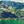 Green mountain landscape with scattered houses and trees overlooking calm lake water