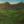 Lush green mountain landscape under blue sky with dense forest and rocky cliffs