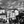 Black and white cityscape with statue, historic church, and people in a lively square