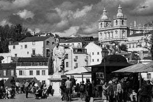 Black and white cityscape with statue, historic buildings, and people in a European square