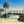 Tropical wooden bridge over calm water with palm trees, rocks, and clear blue sky