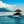 Tropical hut boat cruising on blue ocean with mountains and clouds in the background