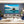 Modern living room with large wall art of a tropical boat on blue ocean, island in background