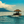 Tropical wooden hut boat on calm blue ocean with distant island and clouds