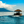 Tropical hut boat on calm blue sea with mountains and clouds in the background
