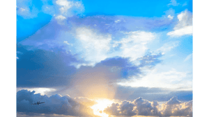 Sunrise with sun rays shining through clouds and blue sky