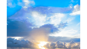 Sunrise with golden rays shining through dramatic clouds and a vibrant blue sky