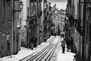 Black and white street photography of a tramway in a European city with people walking