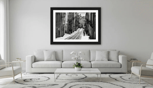 Framed black and white city street photo art displayed above modern white sofa in living room