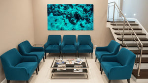 Modern waiting room with blue chairs, glass coffee table, and abstract ocean wall art.