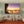 Modern living room with beige sofas, orange rug, and large sunset beach photo wall art.