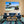 Elegant living room with blue velvet sofa, striped armchairs, and tropical bridge wall art
