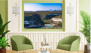 Modern living room with green chairs, wall art landscape of river and lush hills, indoor plants