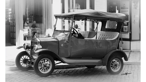 Classic vintage car parked on cobblestone street in black and white