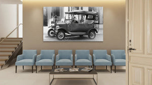 Modern waiting room with blue chairs, coffee table, and wall art of vintage car in black and white