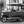 Monochrome photo of a vintage convertible car parked on a cobblestone street.